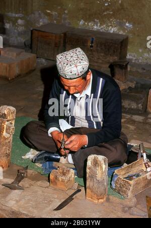 Die kleine von Uiguren dominierte Oase Yengisar (Yingjisha) ist in der gesamten westchinesischen Provinz Xinjiang für die Herstellung von handgefertigten Messern bekannt. Die Kleine Messerfabrik (Pichak Chilik Karakhana/Xiadaochang) beschäftigt erfahrene Handwerker vor Ort, die feine Messer mit eingelegten Griffen herstellen. Fast jeder uigurische Mann trägt ein Messer, sowohl als Zeichen der Manschaft als auch für den utilitareren Zweck, Melonen aufzuschneiden, und die wertvollsten (und teuersten) stammen aus Yengisar. Stockfoto