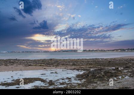 Greenan Shoreline mit Blick über die Bucht in Richtung der Stadt Ayr in der Ferne spät im Nachteron bei Sonnenuntergang. Stockfoto