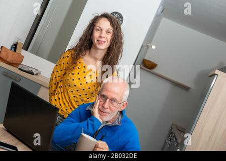 Junge Frau hilft Senioren auf dem Laptop Stockfoto