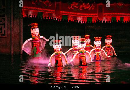 Water Puppetry oder Múa rối nước, wörtlich "Puppen, die auf Wasser tanzen", hat seinen Ursprung im Red River Delta. Die Marionetten sind aus wasserfestem Holz geschnitzt, um traditionelle ländliche Lebensstile und Fabelwesen darzustellen. Hinter der wässrigen Bühne, hüfttief im Wasser stehend, manövrieren die verborgenen Puppenspieler geschickt ihre Holzladen zur Musik eines traditionellen Orchesters. Stockfoto