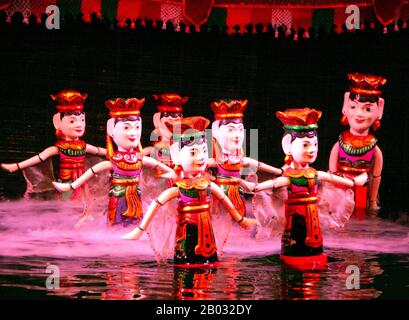 Water Puppetry oder Múa rối nước, wörtlich "Puppen, die auf Wasser tanzen", hat seinen Ursprung im Red River Delta. Die Marionetten sind aus wasserfestem Holz geschnitzt, um traditionelle ländliche Lebensstile und Fabelwesen darzustellen. Hinter der wässrigen Bühne, hüfttief im Wasser stehend, manövrieren die verborgenen Puppenspieler geschickt ihre Holzladen zur Musik eines traditionellen Orchesters. Stockfoto