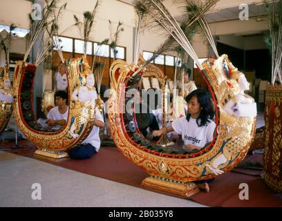 Thailand: Musiker spielen das khong MON, ein gong-Kreisinstrument, in einem traditionellen thailändischen Orchester in Bangkok. Die khong MON ist ein gong-Kreis-Instrument, das mit den Mon-Menschen auf dem südostasiatischen Festland in Verbindung gebracht wird. Er produziert die gleiche Tonhöhe wie der eher verbreitete khong wong gong Kreis, aber anstatt auf dem Boden zu ruhen, erstreckt sich der Holzrahmen des khong MON in Form eines Hufeisens in die Luft. Das Bild einer halb-Mann-halb-Vogel-Figur, die auf den Rahmen geschnitzt ist, ist traditionell und soll einen himmlischen Musiker symbolisieren. Stockfoto