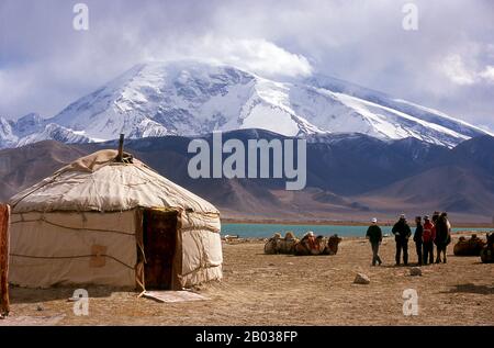 Zwei kleine Siedlungen von Kirghiz (Kirgisisch oder Kirgiz)-Nomaden liegen an der Seite des Karakul-Sees hoch oben im Pamir-Gebirge. Die Besucher können in einem ihrer Wohnmobile oder Yurts übernachten - Kirghiz Männer werden sich den Reisenden nähern, wenn sie am See ankommen, und bieten an, diese Unterkunft zu arrangieren. Die Kirgisen bilden eine der 56 von der Volksrepublik China offiziell anerkannten Ethnien. In China gibt es mehr als 145.000 Kirgisen. Der Zhongba Gonglu oder Karakoram Highway ist ein Ingenieurwunder, das 1986 eröffnet wurde und nach wie vor die höchste asphaltierte Straße der Welt ist. Sie verbindet China a Stockfoto