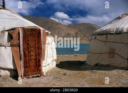 Zwei kleine Siedlungen von Kirghiz (Kirgisisch oder Kirgiz)-Nomaden liegen an der Seite des Karakul-Sees hoch oben im Pamir-Gebirge. Die Besucher können in einem ihrer Wohnmobile oder Yurts übernachten - Kirghiz Männer werden sich den Reisenden nähern, wenn sie am See ankommen, und bieten an, diese Unterkunft zu arrangieren. Die Kirgisen bilden eine der 56 von der Volksrepublik China offiziell anerkannten Ethnien. In China gibt es mehr als 145.000 Kirgisen. Der Zhongba Gonglu oder Karakoram Highway ist ein Ingenieurwunder, das 1986 eröffnet wurde und nach wie vor die höchste asphaltierte Straße der Welt ist. Sie verbindet China a Stockfoto