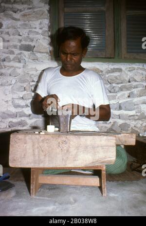 Am östlichen Rand des Süd-Nilandhoo-Atolls liegt die winzige Insel Rinbudhoo. Hier, in einem der ruhigsten und saubersten Dörfer der Malediven, lebt die einzige Gruppe der erblichen Goldschmiede des Landes. Sie schmelzen viktorianische Goldschürfer und Marie-Therèse-Taler so beiläufig wie kürzlich importierte Minispannen aus Dubai, sie stellen eine exquisite Auswahl an Ketten, Halsketten, Ohrringen, Fingerringen und Amuletten her. Asiens kleinste und am wenigsten bekannte Nation, die Republik Malediven, liegt verstreut von Nord nach Süd über einen 750 Kilometer langen Lauf des Indischen Ozeans 500 Kilometer südlich von wes Stockfoto