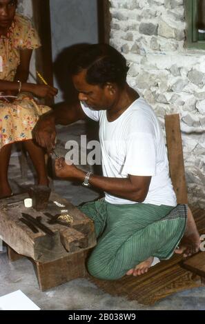 Am östlichen Rand des Süd-Nilandhoo-Atolls liegt die winzige Insel Rinbudhoo. Hier, in einem der ruhigsten und saubersten Dörfer der Malediven, lebt die einzige Gruppe der erblichen Goldschmiede des Landes. Sie schmelzen viktorianische Goldschürfer und Marie-Therèse-Taler so beiläufig wie kürzlich importierte Minispannen aus Dubai, sie stellen eine exquisite Auswahl an Ketten, Halsketten, Ohrringen, Fingerringen und Amuletten her. Asiens kleinste und am wenigsten bekannte Nation, die Republik Malediven, liegt verstreut von Nord nach Süd über einen 750 Kilometer langen Lauf des Indischen Ozeans 500 Kilometer südlich von wes Stockfoto