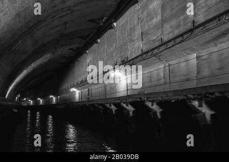 Tunnelperspektive aus dunklem Beton, Teil des verlassenen U-Boot-Untergrunds aus der Zeit der UdSSR. Balaklava, Krim. Schwarz und Weiß Stockfoto