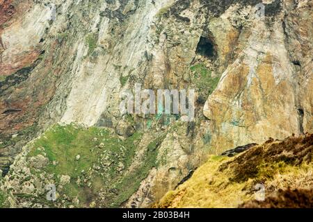 Nahaufnahme der Klippen, die von Mineralien und Kupfer bestackt wurden, in Cligga Head bei Perranporth und St Agnes, Cornwall, England Stockfoto