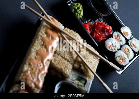 Set mit Brötchen und Sushi in Plastikboxen für unterwegs. Sushi-Lieferung zu Hause. Stockfoto