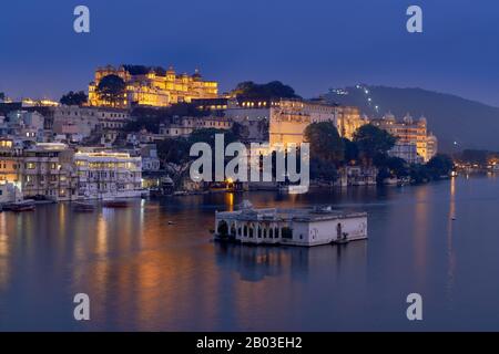 Nacht über den Pichola-See auf den beleuchteten Stadtpalast und den Taj Fateh Prakash Palast von Udaipur, Rajasthan, Indien Stockfoto