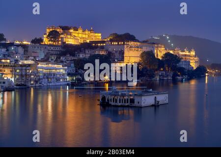 Nacht über den Pichola-See auf den beleuchteten Stadtpalast und den Taj Fateh Prakash Palast von Udaipur, Rajasthan, Indien Stockfoto