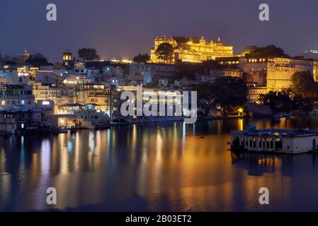 Nachtaufnahme ueber Pichola-See auf beleuchteten Stadtpalast und Taj Fateh Prakash Palast von Udaipur, Rajasthan, Indien Nacht über den Pichola-See geschossen Stockfoto