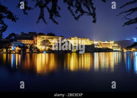 Nacht über den Pichola-See auf den beleuchteten Stadtpalast und den Taj Fateh Prakash Palast von Udaipur, Rajasthan, Indien Stockfoto