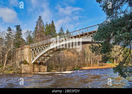 CARRON VILLAGE MORAY SCOTLAND EIN BLICK AUF DIE STRUKTUR DER EINZIGARTIGEN CARRON ROAD UND DER ALTEN EISENBAHNBRÜCKE, DIE DEN FLUSS SPEY UND EINE GRÜNE FISCHERHUT A ÜBERQUERT Stockfoto