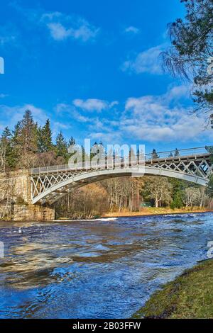 CARRON VILLAGE MORAY SCOTLAND EIN BLICK AUF DIE STRUKTUR DER EINZIGARTIGEN CARRON ROAD UND DER ALTEN EISENBAHNBRÜCKE, DIE DEN FLUSS SPEY UND EINE GRÜNE FISCHERHUT ÜBERQUERT Stockfoto