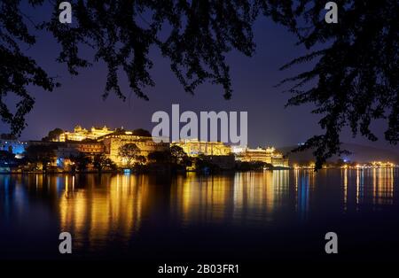 Nacht über den Pichola-See auf den beleuchteten Stadtpalast und den Taj Fateh Prakash Palast von Udaipur, Rajasthan, Indien Stockfoto