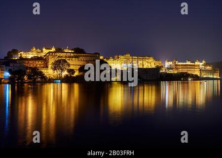 Nacht über den Pichola-See auf den beleuchteten Stadtpalast und den Taj Fateh Prakash Palast von Udaipur, Rajasthan, Indien Stockfoto