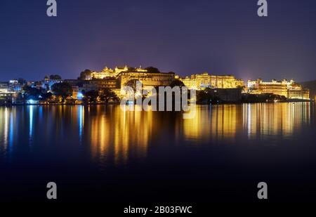 Nacht über den Pichola-See auf den beleuchteten Stadtpalast und den Taj Fateh Prakash Palast von Udaipur, Rajasthan, Indien Stockfoto