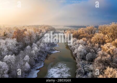 Budapest, Ungarn - Frostbäume bei Sonnenaufgang mit Eisenbahnbrücke und Insel zur Winterzeit Stockfoto