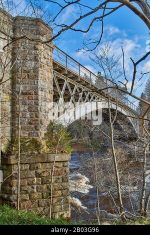 CARRON VILLAGE MORAY SCOTLAND WINTERBÄUME AM UFER UMGEBEN DIE EINZIGARTIGE CARRON ROAD UND DIE ALTE EISENBAHNBRÜCKE, DIE DEN FLUSS SPEY ÜBERQUERT Stockfoto