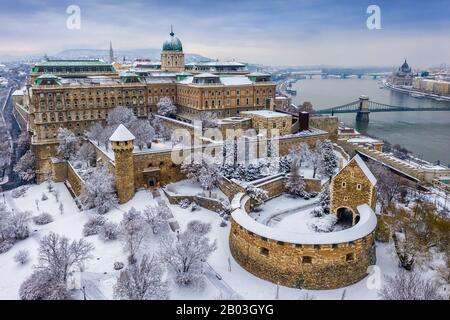 Budapest, Ungarn - Luftbild des verschneiten Königspalastes Buda von oben mit der Szechenyi-Kettenbrücke und dem ungarischen Parlament im Winter t Stockfoto