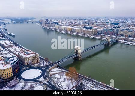 Budapest, Ungarn - Blick Auf Die Skyline Von Budapest im Winter mit dem schneereichen Clark Adam Platz, der Szechenyi Kettenbrücke und dem ungarischen Parlament auf A Stockfoto