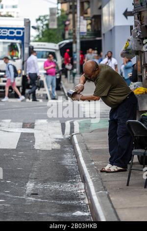 New York City, USA - 6. Juni 2019: Ein Straßenverkäufer wäscht einen Becher mit Getränken und gießt auf der Straße Schmutzwasser Stockfoto