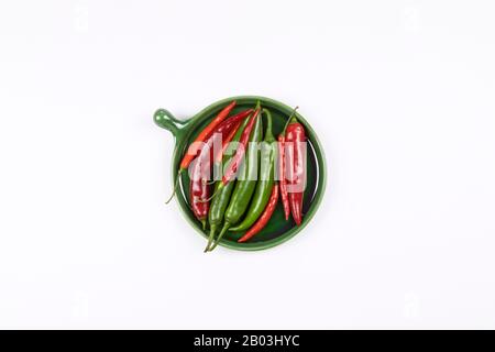 Nahaufnahme von roten und grünen heißen Paprika auf grüner Platte flach lag, weißer Hintergrund. Stockfoto