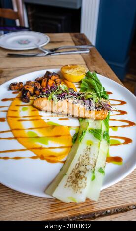 Typisches Pub-Essen: Sesam verkrusteter Lachs mit verkohlter Pak Choy, Süßkartoffel und Teriyake-Dressing, serviert auf einem weißen china-teller Stockfoto