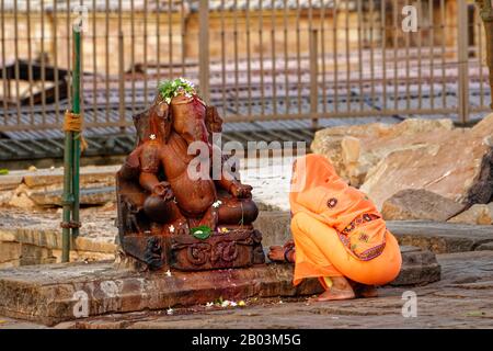 Die indische Frau kauerte vor einer Statue von Lord Ganesha, Khajuraho, Madhya Pradesh, Indien Stockfoto