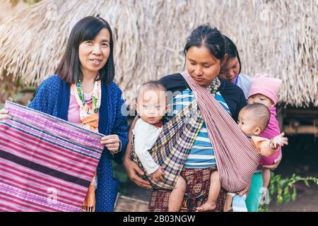 LAMPHUN THAILAND - 8. Dezember: Nicht identifizierte weibliche Touristen ein Bild mit Karen Familie auf Dezember 8,2019 bei Karen Dorf in Lamphun, Thailand Stockfoto