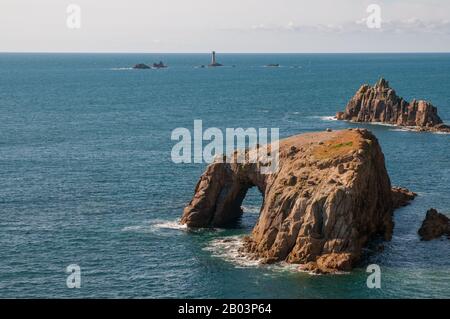 Blick über die Keltische See von Land's End, Cornwall, mit Enys Dodnan Arch im Vordergrund und Longshices Lighthouse in der Ferne. Stockfoto