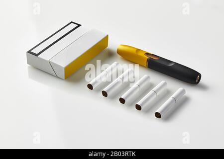 Schwarze und gelbe E-Zigarette der neuen Generation, eine Packung und fünf  Heatsticks, isoliert auf Weiß. Neue alternative Technologie.  Heiztabak-System Stockfotografie