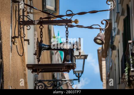 Ein Sawing-Automat hängt in der Altstadt als Werbeschild für einen Dress Maker-Laden, der Änderungen vornahm, Alghero, Sardinien, Italien. Stockfoto