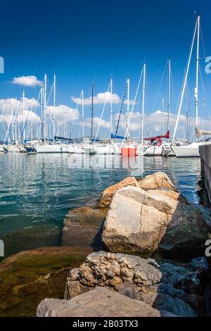 Auf einem Spaziergang durch das Hafengebiet mit Blick auf alle Yatchs und kleinen Boote, Alghero, Sardinien an einem sonnigen Tag, Italien, Eastern Medite Stockfoto