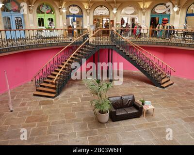 Große Doppeltreppe aus Metall mit Holzpflaster gegen rosafarbene Wände in der Corn Exchange in Leeds Yorkshire England Stockfoto