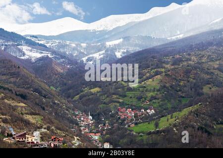 Blick über ein Bergdorf mit schneebedeckten Bergen im Hintergrund, im Kosovo Stockfoto