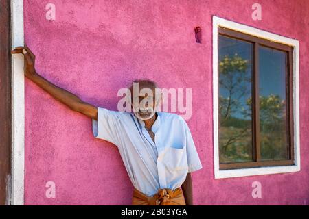 Älterer Mann gegen die rosafarbene Mauer im Dorf Nuwara Eliya, Sri Lanka Stockfoto