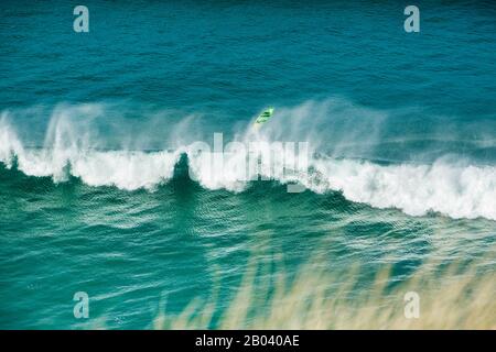 Ein Surfbrett fliegt hoch über einer Welle, als ein Surfer die Kontrolle vor Perran Beach, Perranporth, der Küste von Cornwall, Cornwall England verliert Stockfoto