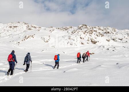 Spaziergänger in Langdales genießen frischen Schnee und Sonnenschein Stockfoto