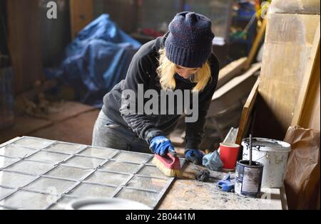 Frau Buntglas arbeitende Reinigungsplatte aus Klarglas bei der Altbau-Sanierung. Arbeiten vor Ort. Stockfoto