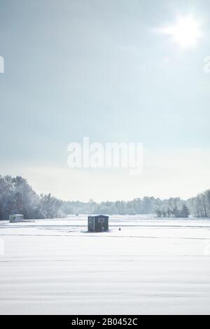 Eisangeln an einem hellen Wintermorgen an einem See in Minnesota mit Buben und Anhängern Stockfoto