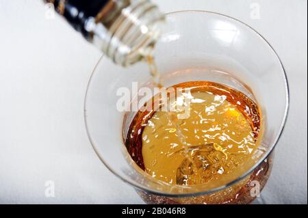 Whisky wird in Glas gegossen. Draufsicht auf Glas mit Getränk. Stockfoto