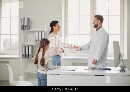 Mutter mit Tochter schüttelt mit dem Arzt, der in der Klinik im Klinikum steht, die Hände. Stockfoto