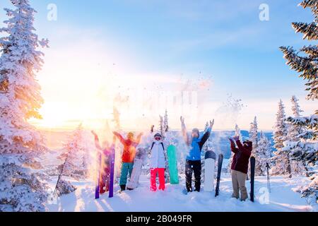 Eine Gruppe von Snowboardern und Skifahrerfrühs mit Snowboards freut sich über die Sonne im Winterwald bei Sonnenaufgang. Konzept Lebensstil, Reisen Stockfoto