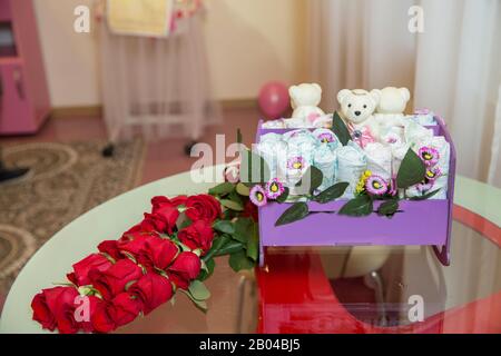 Weiße Spielzeugpuppe. Blumenstrauß im gegenüberliegenden Spiegel . Spiegelung eines Hochzeitsbouquets aus Glas, Spiegel. Eine Blumenarrangement aus Rosetten Stockfoto