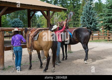 Cowgirls (Wranglers) mit ihren Pferden in Averill's Flathead Lake Lodge, einer Dude Ranch in der Nähe von Kalispell, Montana, Vereinigte Staaten. Stockfoto