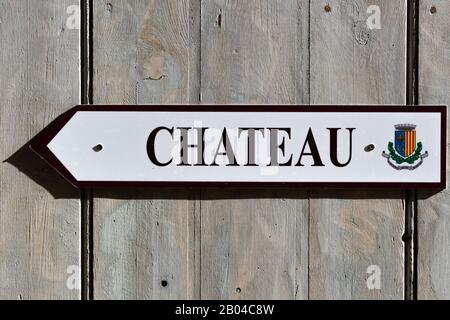 Ein Pfeilschild, der auf das Schloss ('château') zeigt, das in Französisch in einem Bergdorf steht Stockfoto