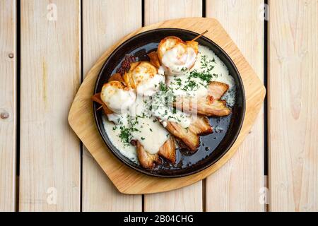 Blick auf dünne Pfannkuchen auf einem mit Käse gefüllten Spieß, serviert mit gebratenem Speck Stockfoto