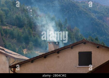 Rauch, der im Winter aus einem Kamin eines Hauses in den Bergen kommt Stockfoto